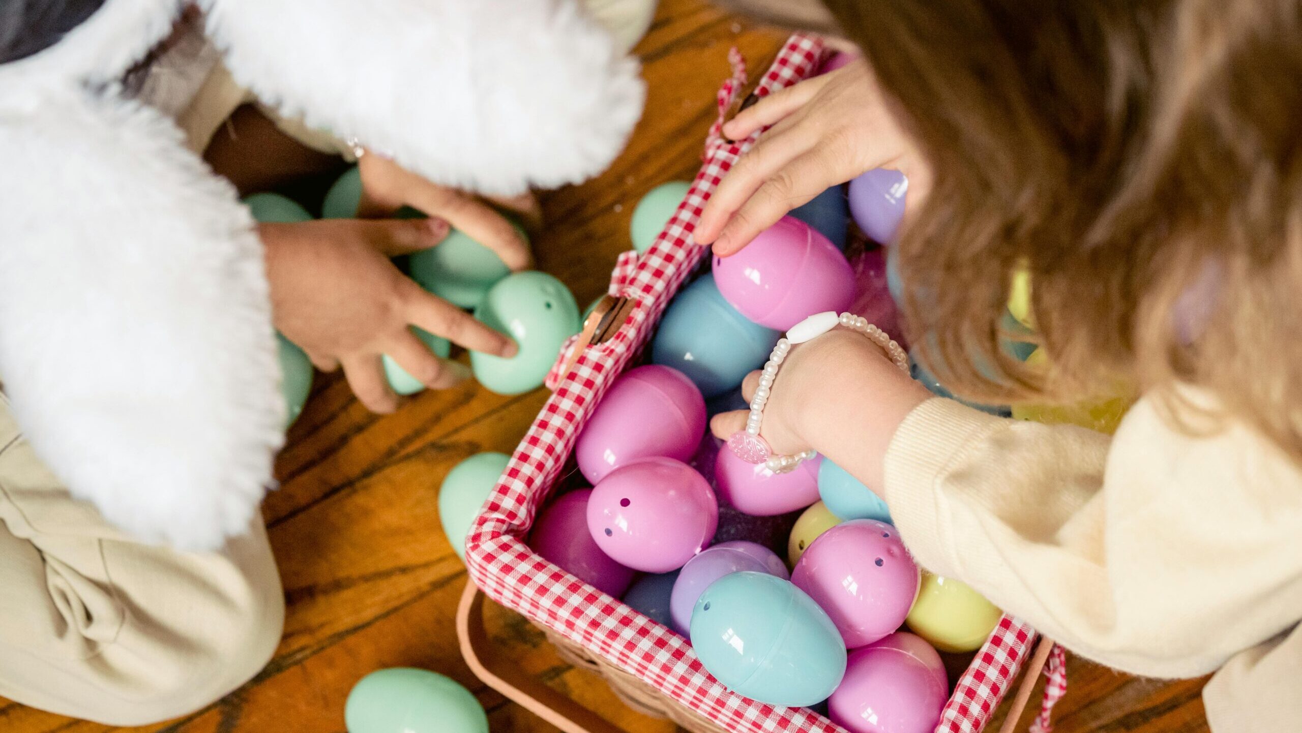pexels-eren-li-7169628 Photo of two small children looking through a basket of bright colored plastic eggs